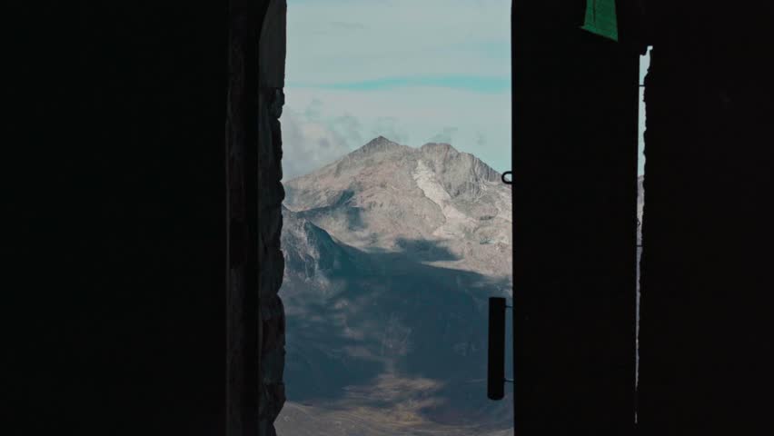 A creative, low-key shot of a rugged peak in the Cordillera Real range. The sunlit Huayna Potosí mountain is framed by a dark silhouette, highlighting the dramatic high-altitude landscape of Bolivia.
