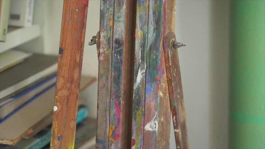 Close up of a colourful well used easel stand in an art studio