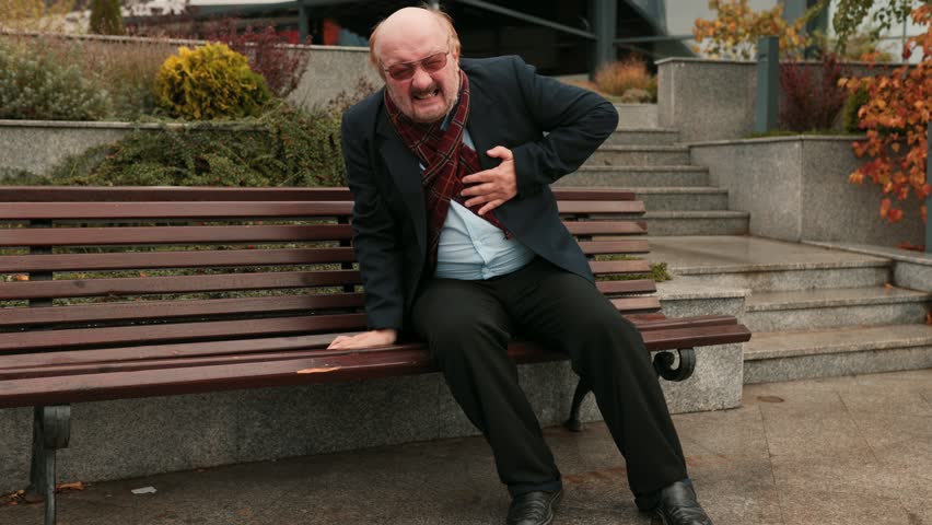 Outdoor Heart Crisis A distressed senior bearded man, feeling unwell and anxious, suffers sudden chest pain, potentially signaling a heart attack in the city.