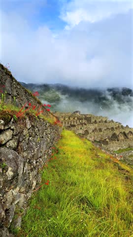 Morning sunrise Machu Picchu Inca trail tourist circuit terrances landscape sunny foggy clouds Peruvian Andes Peru Perú historic Inca Sanctuary Temple rainy season lush green jungle Vertical pan right