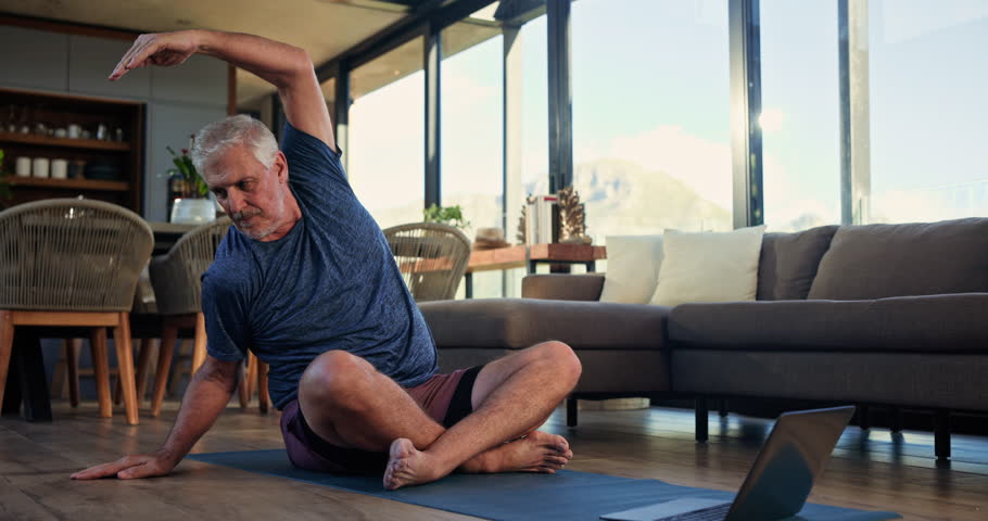 Man, stretching and pilates with laptop, home and workout routine in lounge, online and flexibility. Happy, mature person and exercise preparation on floor, balance and tips on web or tech in house