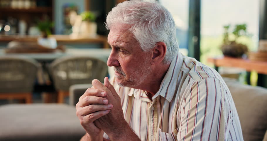 Senior man, thinking and sad on sofa in home with stress, mental health and worry in retirement. Elderly person with depression, anxiety or bad memory on couch, ptsd and reflection at apartment