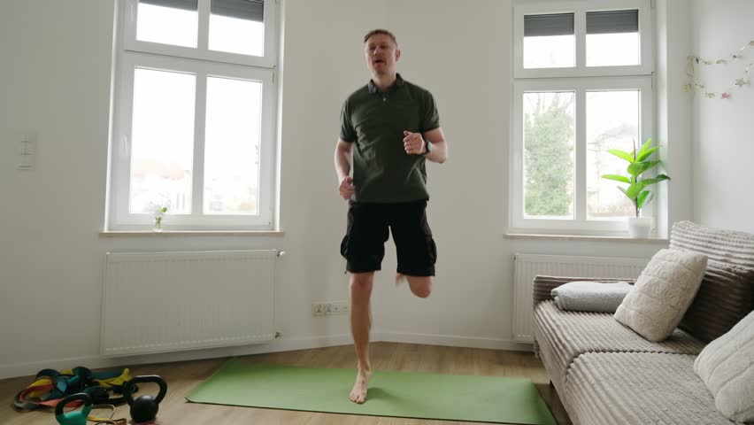 Man Jumping With Backward Leg Kicks Doing Sport At Home