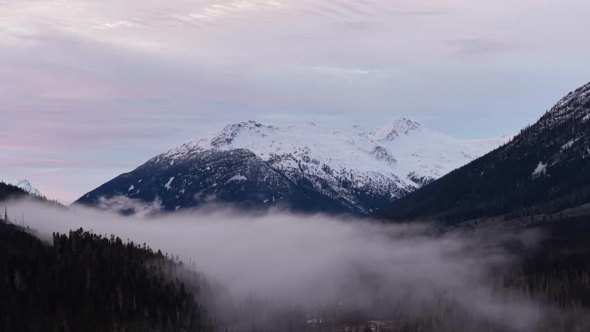 Majestic Snow-Capped Mountains Over a Misty Forest Valley in British Columbia, Canada
