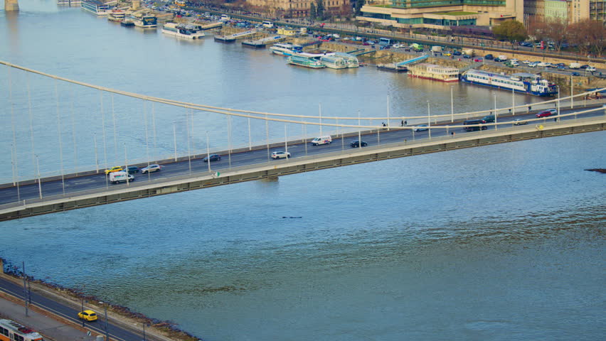 Boat passing beneath a large city bridge on a river, showing water motion and urban structure