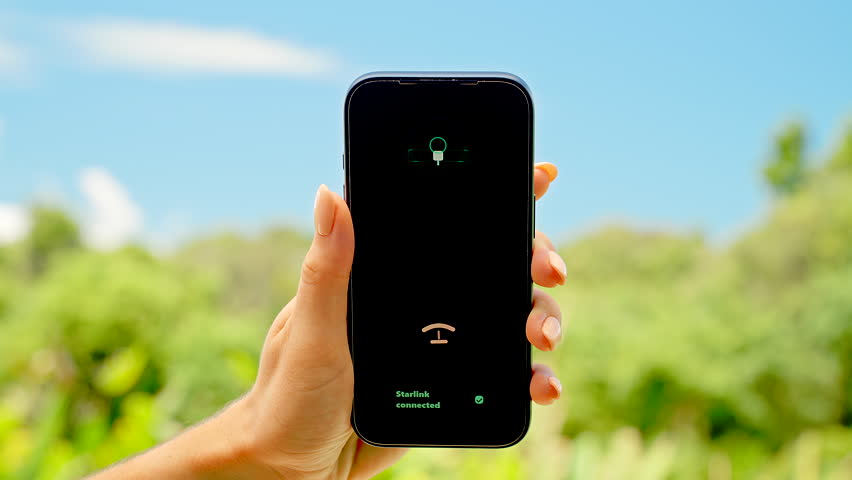 Smartphone in Hand Showing Starlink Connected Screen with Sunny Green Grass and Bright Blue Sky Background, Concept Digital Freedom and Global Internet Access.