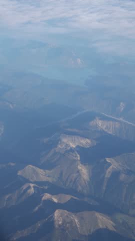 Alpine mountains visible from a plain that is flying over clouds