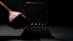 Hand Starting Newton’s Cradle Motion. Hand Releasing Newton’s Cradle Balls. Classic Newton’s Cradle Physics Concept. - Powered by Shutterstock - Get 15% off with code: PIKWIZARD15
