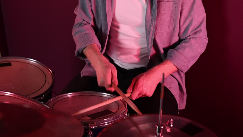Man playing drums with drumsticks in studio, closeup