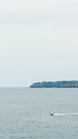 The coast of Thailand on a cloudy day, beach entertainment - parachute behind a motorboat, people parachute over the sea