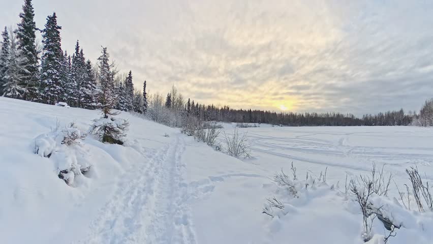 A beautiful winter sunset over snow covered pine trees and frozen lake. Winter landscape with lot of snow. Alaska.