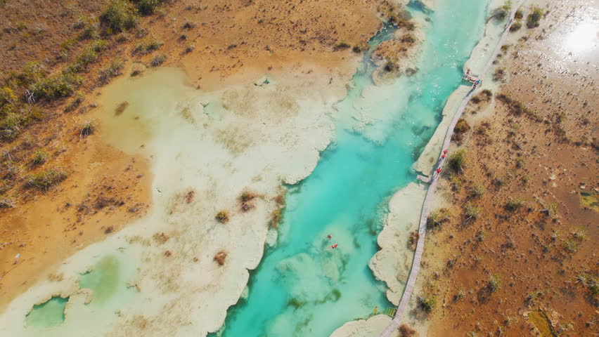 Aerial of swimmers in turquoise water of canal Los Rapidos in Bacalar Mexico