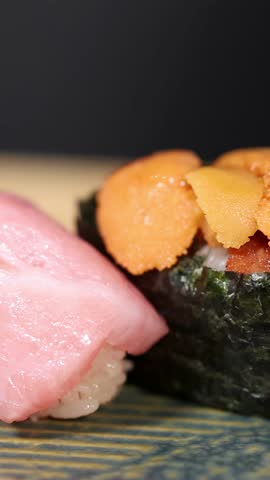 Macro shot of fatty tuna and sea urchin sushi on a textured ceramic plate