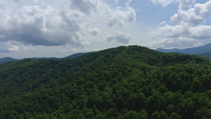Panoramic View of Green Mountain Range Lush forested mountains under cloudy sky
