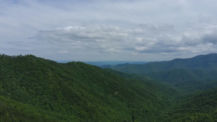 Panoramic View of Green Mountain Range Lush forested mountains under cloudy sky