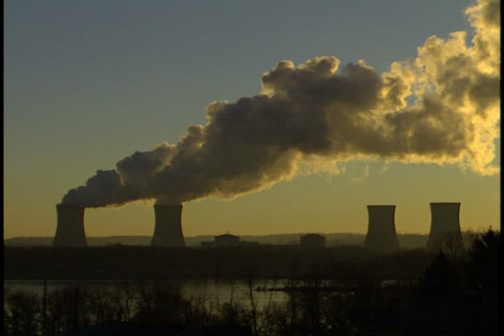 WS of four cooling towers at sunrise in Harrisburg, Pennsylvania. The two leftmost towers are billowing thick plumes of white smoke. The Susquehanna River is in the foreground.