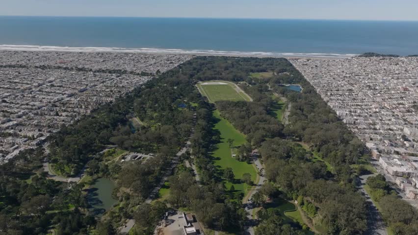 Aerial panoramic view of Golden Gate Park’s lush greenery beside dense residential urban districts along the Pacific coast in San Francisco, California.