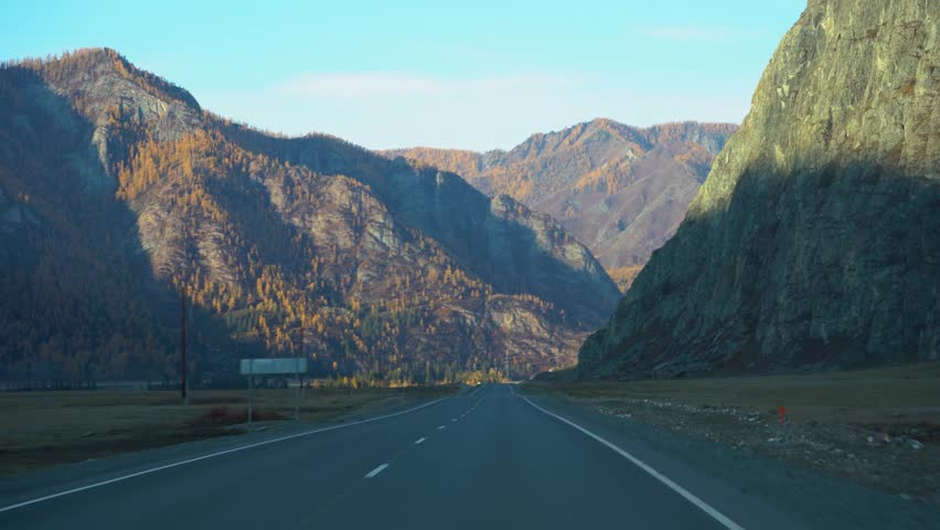 Quiet Rocky Journey, Solitary Roadway With Steep Cliffs And Distant Rolling Hills On Both Sides, Isolated Mountain Highway Flanked By High Rocky Cliffs And Expansive Distant Landscapes