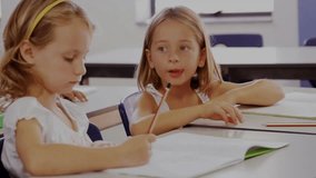 Two girls at classroom desk, right girl speaking initiating hex overlay mapping facial pencil notes. Collaboration, friendship, education, digital, connectivity, innovation, focus - Powered by Shutterstock - Get 15% off with code: PIKWIZARD15