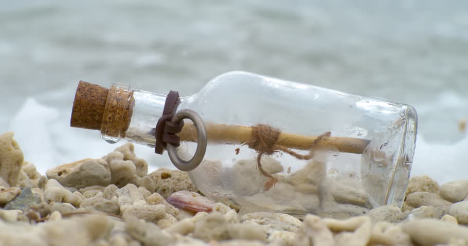 Message in the bottle on a sand beach. Shot on super slow motion camera 1000 fps.