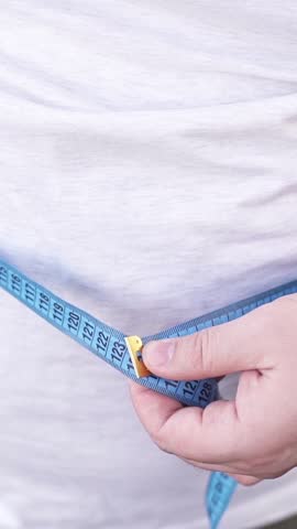 A fat man measures his waist and big belly with a ruler