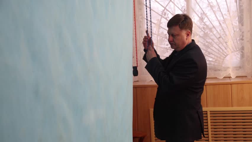 Photographer raising a blue backdrop for a portrait photography session in a professional photo studio.