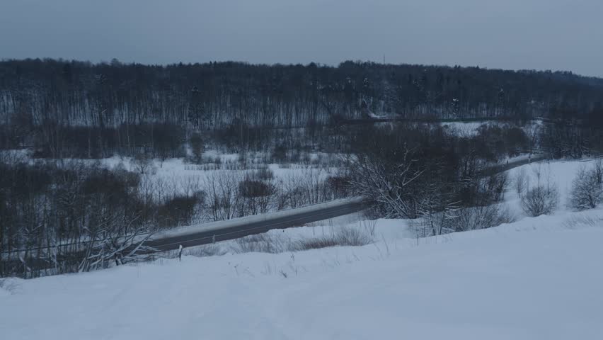 Snowy Hill Overlooking Winter Road and Forest Valley with Calm Traffic, Peaceful Winter Landscape, 4K
