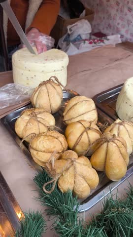 Vendor slicing traditional farmer cheese at outdoor food market. Local dairy products displayed on a counter, authentic street food experience, slow food concept and regional cuisine.
