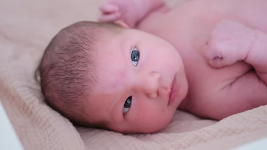 Newborn baby with blue eyes looking at camera