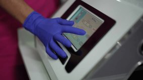 Gloved hand taps touchscreen medical console, purple nitrile glove closeup of control panel adjusting treatment settings with precise fingertip interaction - Powered by Shutterstock - Get 15% off with code: PIKWIZARD15