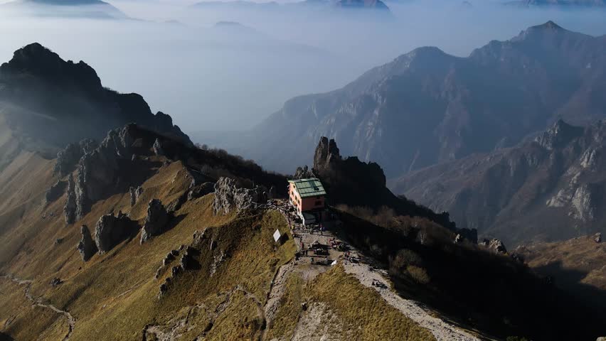 Aerial view of Rifugio Rosalba on the slopes of Grigna Meridionale, overlooking Lake Como, alpine ridges, hiking trails and dramatic Lombardy scenery. Drone Birds Eye view of Piani dei Resinelli in Lecco, north Italy. Italian Mountains.