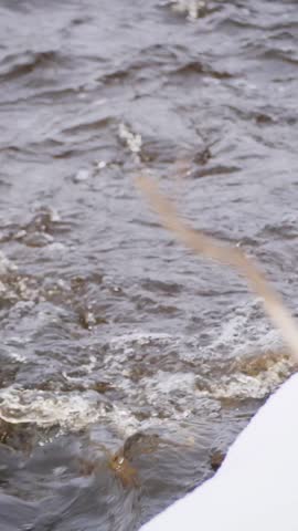 Rapid Winter Stream Flowing with White Foam and Dark Ripples - Close-up of Churning River Water with Splashing Waves in Winter