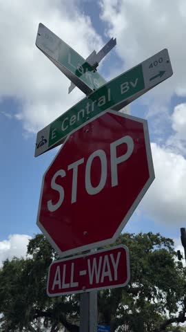 DOLLY SHOT - Orlando Road Sign in downtown Orlando, Florida, USA. Traffic signs STOP, red and white "All-way" sign. Direction sign to E Central Blvd and Lake Eola.
