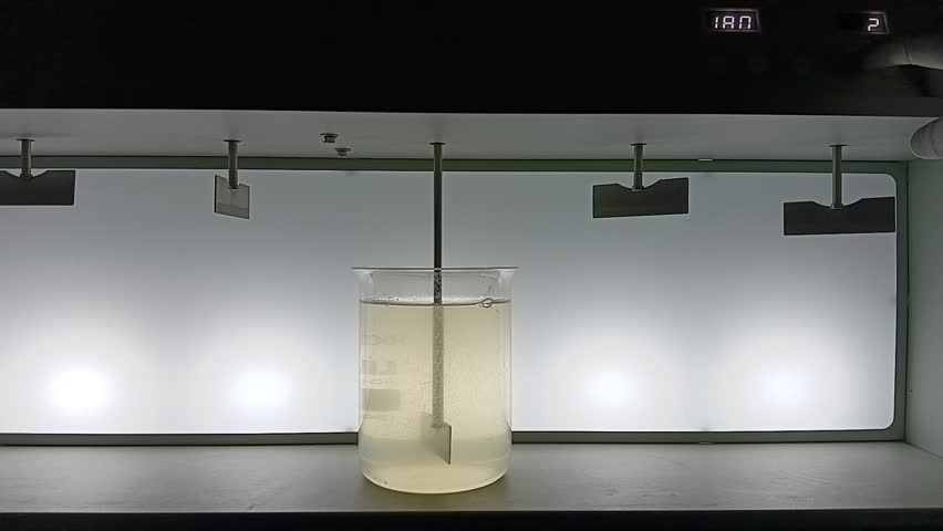 Adding chemicals to raw water and starting rapid mixing stage of a jar test to initiate coagulation in a water treatment lab.