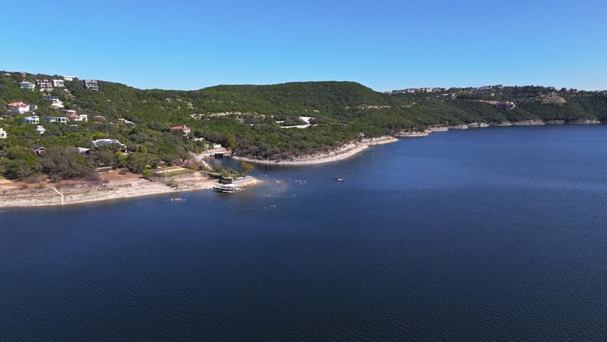 High aerial push in shot of breathtaking Lake Travis on a sunny autumn day, with rugged bluffs and stunning lakeshore homes, Austin, Texas