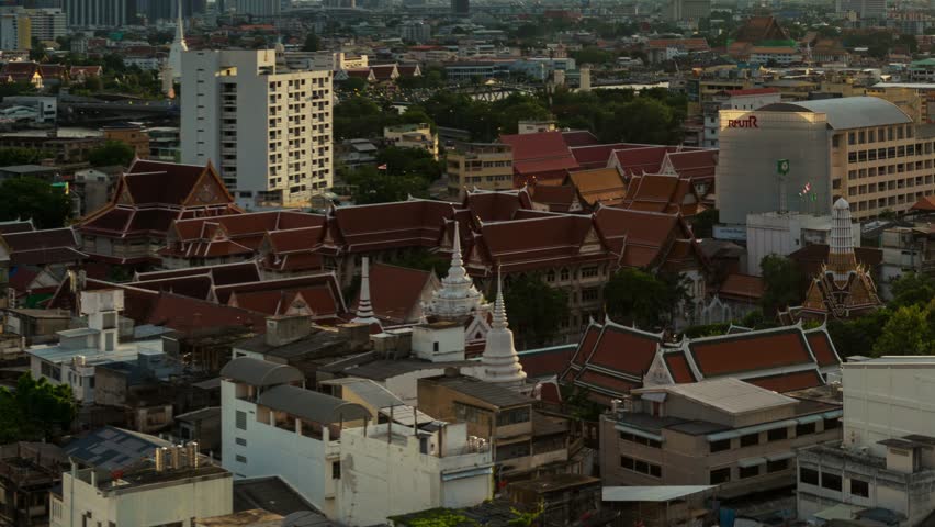 Timelapsing view of temple and skyline with urban buildings at night in Bangkok, Thailand.