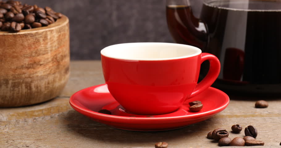 Pouring aromatic coffee into cup at wooden table, closeup