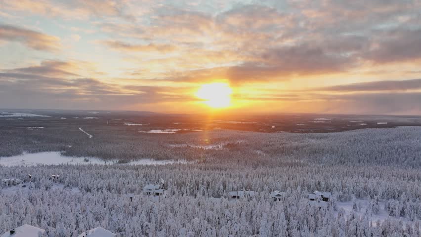 Stunning aerial sunset over snowy forest in Lapland winter landscape with frost covered pine trees