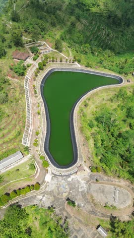 Aerial View Of Lush Mountain Ridge With Terraced Fields And Hidden Reservoir