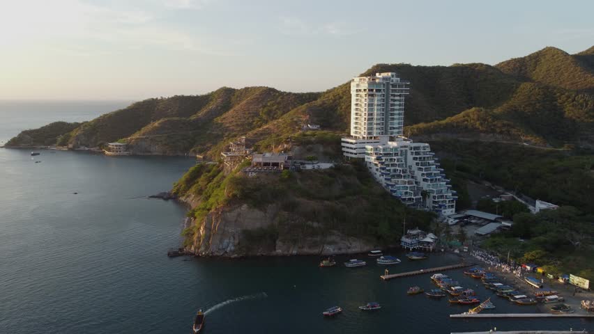 Aerial sunset view of El Rodadero beach and skyline in Santa Marta, Colombia, with people and boats.