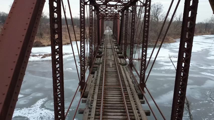 Flying above an abandoned train track crossing a frozen river.