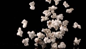 White fluffy pieces of popcorn fall in slow motion against a black background and bounce off each other. - Powered by Shutterstock - Get 15% off with code: PIKWIZARD15