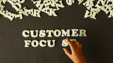 A person spelling Customer Focused With Plastic Letters