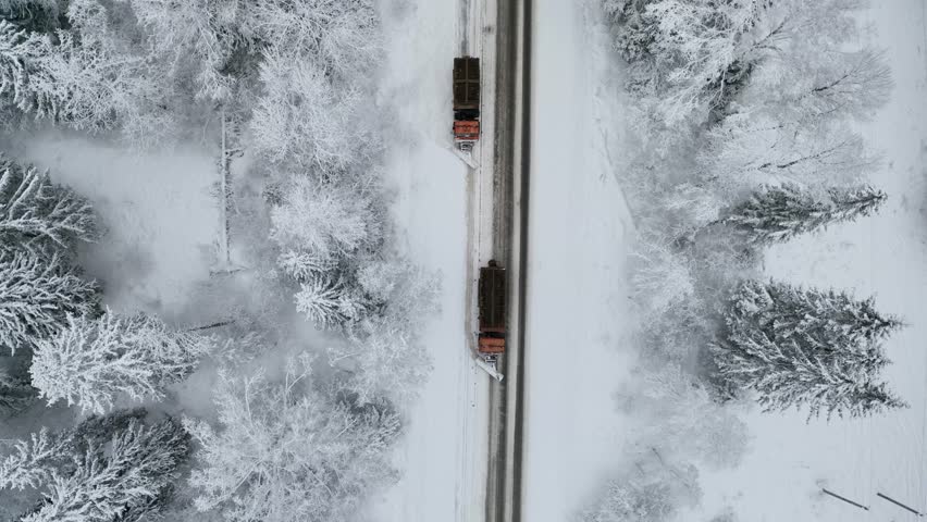 Aerial top view of Snow plow truck on snowy road in action. Snow plows clearing highway during blizzard. Hard weather condition in winter. 