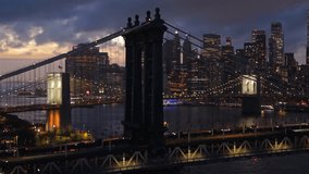 Cinematic aerial night view of Brooklyn Bridge with Manhattan skyline, glowing skyscrapers, river reflections and dramatic dusk sky, capturing iconic New York City urban travel destination - Powered by Shutterstock - Get 15% off with code: PIKWIZARD15