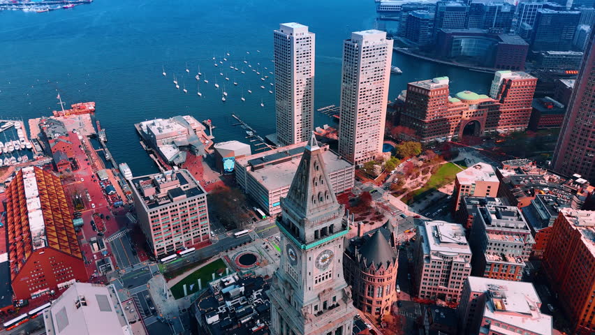 Old buildings on the harbor of Boston, Massachusetts, USA. Drone approaches blue waterscape with sailboats on.