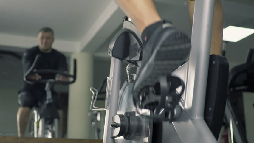 Young man exercises on stationary training bike in gym cardio session