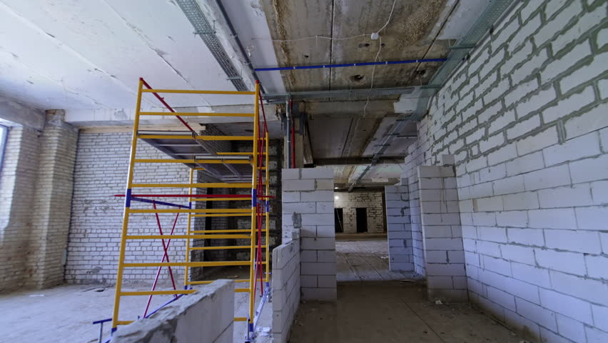 Scaffolding inside the premises of the constructed building. White brick walls newly built in the interior.