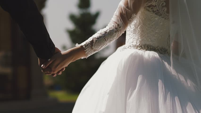 Bride and groom holding hands, celebrating love and unity on their wedding day, capturing romance, commitment, and a joyful matrimonial moment.