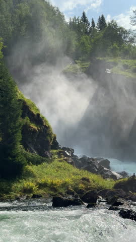 Powerful misty waterfall crashing into a rushing river in norway